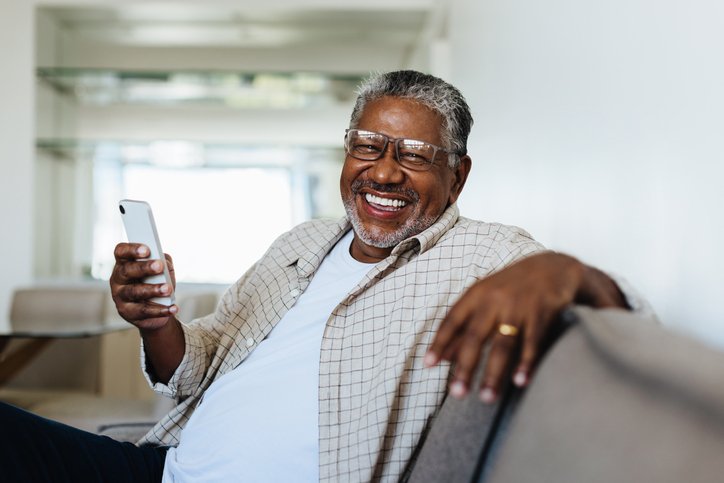 Foto de homem sorrindo e usando smartphone.